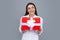 Woman with gift. Portrait of excited young girl holding gift box, isolated grey background. Pretty girl with present.