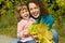 Woman and girl laugh with leaves in garden