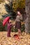 Woman and girl with umbrella in autumn forest portrait outdoor, yellow leaves background