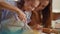 Woman and girl whisking eggs on kitchen. Daughter and mother cooking together