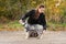 Woman gives a command to her dog puppy Siberian Husky in the autumn park. Dog training