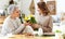 Woman giving bouqet of tulips to excited elegant elderly mother while having breakfast together