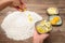 Woman giving lemon zest on flour, butter and eggs on the side, c