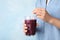 Woman with glass of fresh acai drink and straw on blue background, closeup. Space for text