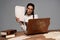Woman in glasses with documents and vintage laptop at workplace isolated on grey