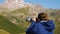 A woman with glasses looking through tourist binoculars at the mountains. A girl in a windbreaker against the backdrop