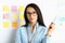 Woman in glasses with pen in her hands stands next to white board