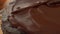 Woman glazing a chocolate cake with an offset spatula