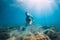 Woman glides with sand in hand. Free diver with fins posing underwater