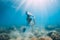 Woman glides with sand in hand. Free diver with fins posing underwater