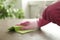 Woman in gloves cleaning brown marble table with spray detergent and rag, closeup