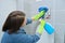 Woman in gloves cleaning and polishing chrome toilet button on tiled wall