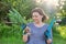 Woman in gloves with garden shovel holding bunch of fresh green onions