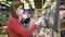 Woman in gloves and mask weighs apples touch screen electronic scales in supermarket, coronavirus in public place