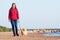 Woman go with her dog on the beach. girl with Pomeranian spitz walking along the seashore