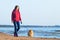 Woman go with her dog on the beach. girl with Pomeranian spitz walking along the seashore