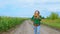 A woman goes along a cornfield on a dirt road