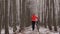 The woman goes with bicycle on a path in the wood. Women in an orange jacket walks with a dog. Sporty girl riding a bike