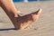 Woman going on the beach and risking of stepping on a splinter of broken bottle glass, which is lying on the littered