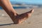 Woman going on the beach and risking of stepping on a splinter of broken bottle glass, which is lying on the littered