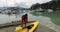 Woman going kayaking in Squamish preparing kayak. View of Squamish Harbour, boats and mountains. British Columbia