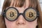 Woman with golden bitcoins in glasses