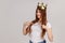 Woman with golden crown on head pointing herself and looking at camera, declaring her authority,