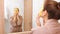 Woman with golden mask does face massage at hotel mirror