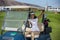 Woman in golf cart on field greeting friends