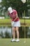 Woman golfer approach for hitting golf ball on green