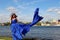 woman in a gorgeous long blue dress like a fishtail. portrait in full growth on the banks of the river, in a windy warm summer day