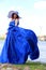 woman in a gorgeous long blue dress. portrait in full growth on the banks of the river, in a windy warm summer day