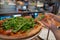 Woman grabbing slice of pizza with arugula greens on top