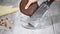 Woman grates chocolate dough in the glass bowl.