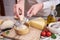 Woman grates Parmesan cheese on a wooden cutting board at domestic kitchen