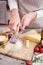 Woman grates Parmesan cheese on a wooden cutting board at domestic kitchen