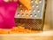 Woman grating carrot on metal grater