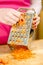 Woman grating carrot on metal grater