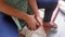 Woman grating mature coconut using traditional ingenious coconut grater where she sits on