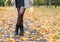 Woman in gray coat standing on alley of city park. legs closeup