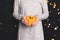 Woman in gray dress hold in hands little decorative pumpkin.