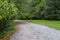 A woman in a gray shirt walking down a long winding dirt hiking trail covered with fallen autumn leaves