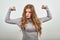 Woman in gray shows her muscles on arms demonstrating strength confidence power