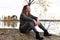 Woman in gray sits on stones by the lake in autumn