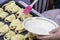 A woman greases the pies prepared for baking with egg yolk for shine