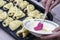 A woman greases the pies prepared for baking with egg yolk for shine