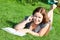 Woman on green grass reading book and speaking on phone