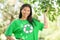 Woman in green recycling t-shirt touching leaves at park