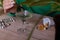 a woman in a green sweater adds drops of chlorophyll to a glass of water standing next to palm trees