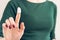 Woman in a green T-shirt and a maroon manicure shows hand cream